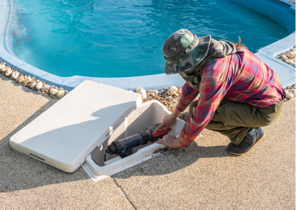 Plumber inspects a pipe near a pool